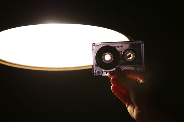 A tape from the tape recorder being held in front of a light in interrogation room.