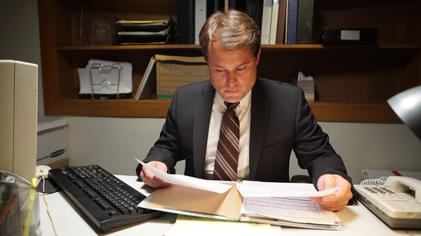 Reconstruction of actor of a second detective working at desk.