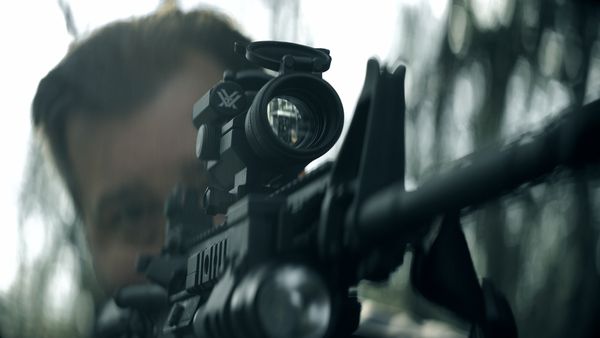 Reenactment of Todd Kohlhepp (Casey Radmann) aiming a scoped rifle.