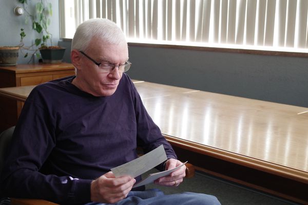 Portrait of Mark Wangler looking at pictures of his family.